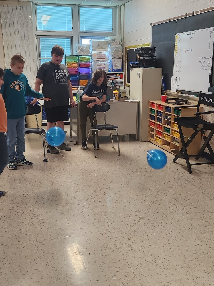 students raising balloons down a string