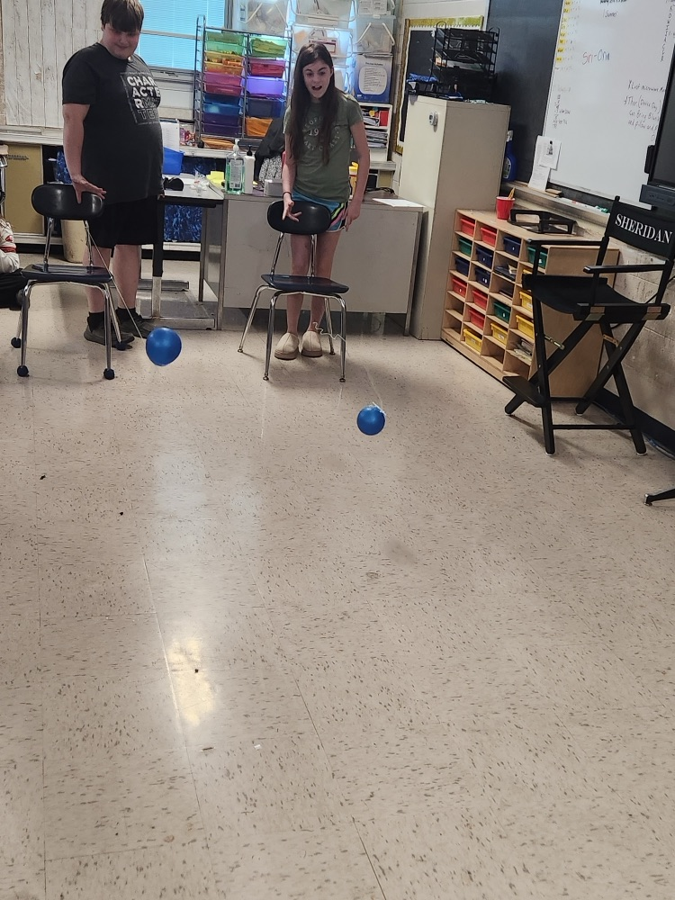 students raising balloons down a string