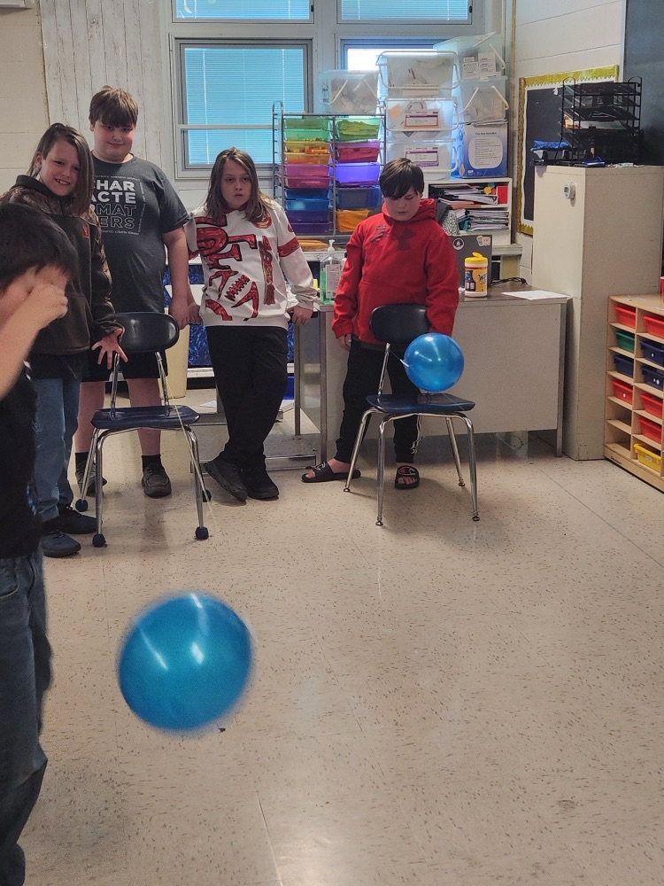 students raising balloons down a string