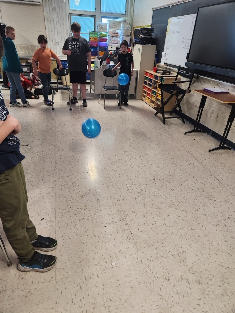 students raising balloons down a string