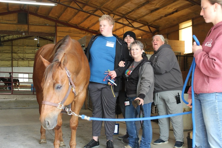 boy and teachers beside horse