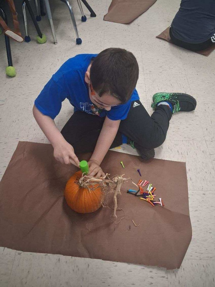 student hammering tees into pumpkin 