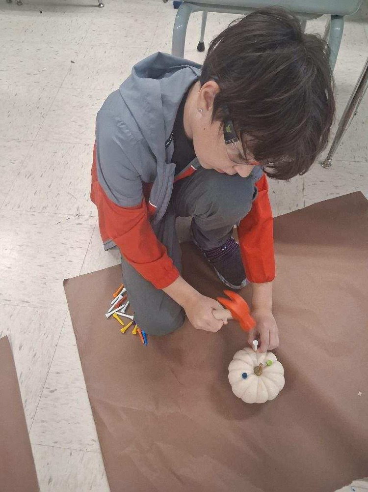 student hammering tees into pumpkin 