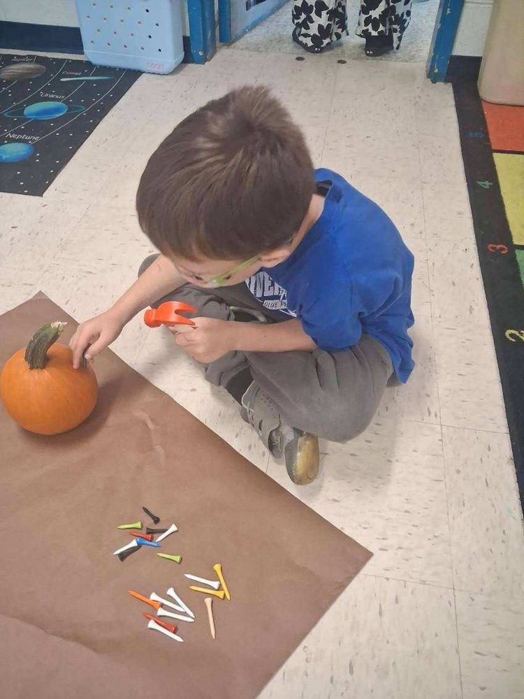 student hammering tees into pumpkin 