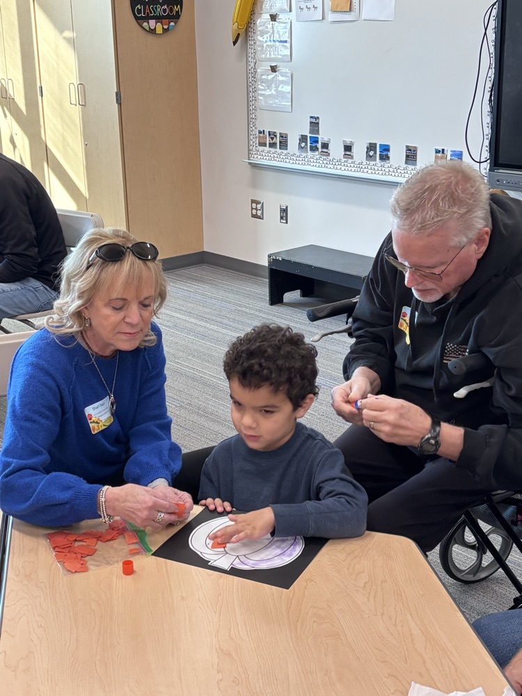 student doing a craft with grandparents