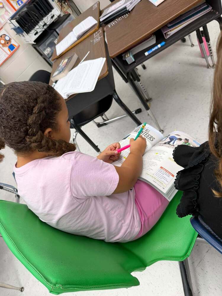 a 3rd grader writes in the margins while studying a book