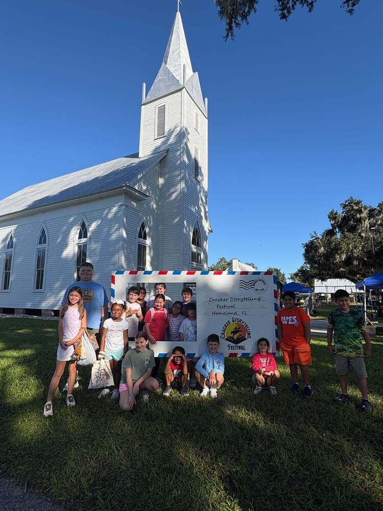 group of students with a giant envelope cutout that reads, "Cracker Storytelling Festival, Homeland Fl"