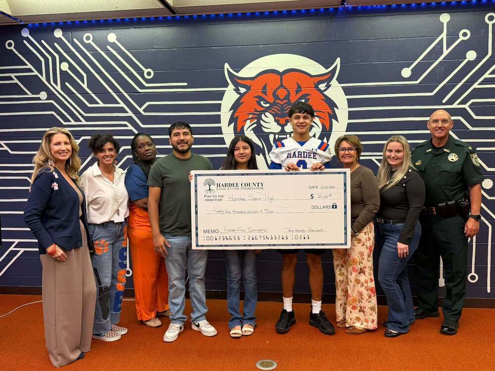 a group of teachers and students holding a giant check
