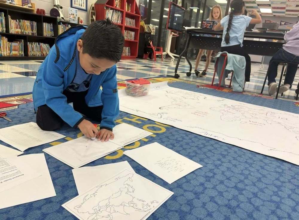 boy on the floor coloring world maps