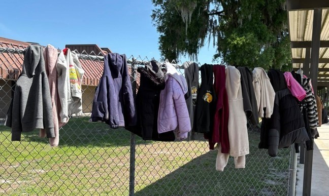 lost and found jackets hanging on a fence
