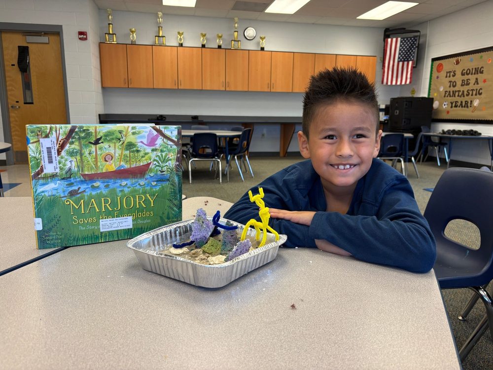 Student with model and book called "Marjory saves the everglades"