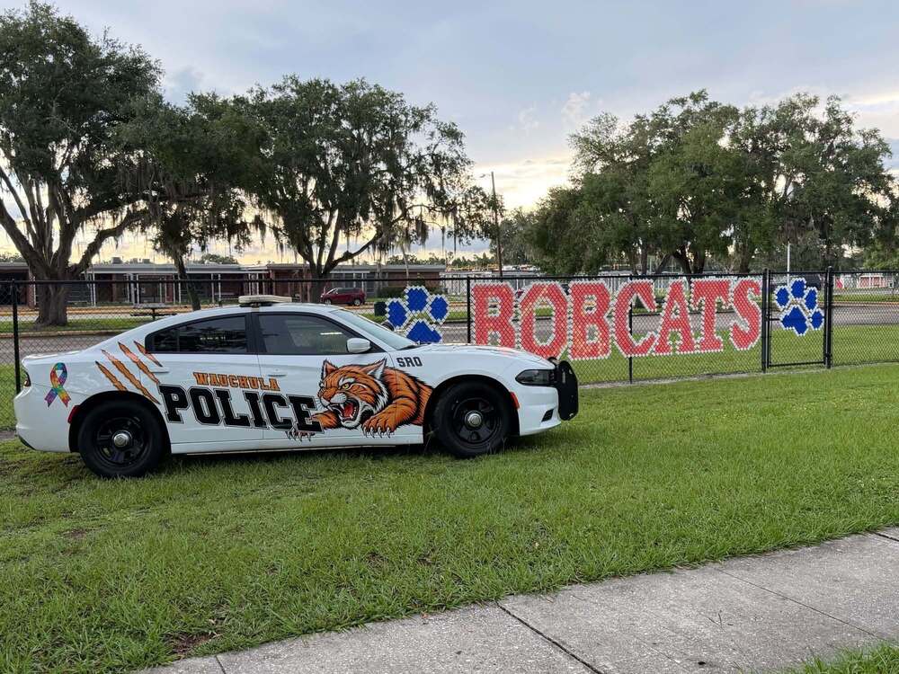 police car next to bobcats written on a fence