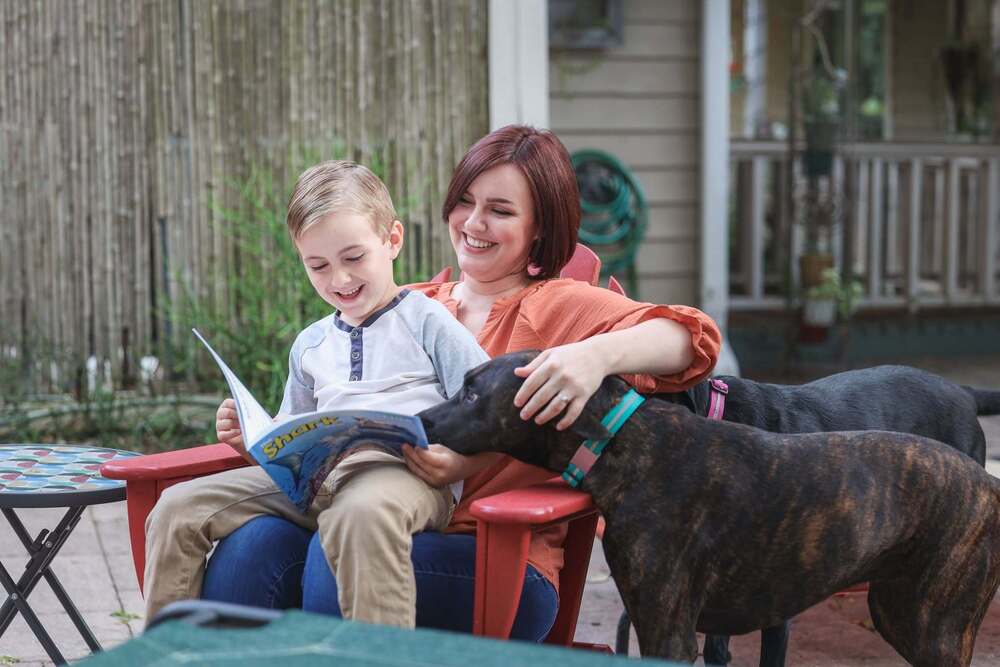 child reading to a woman and a dog