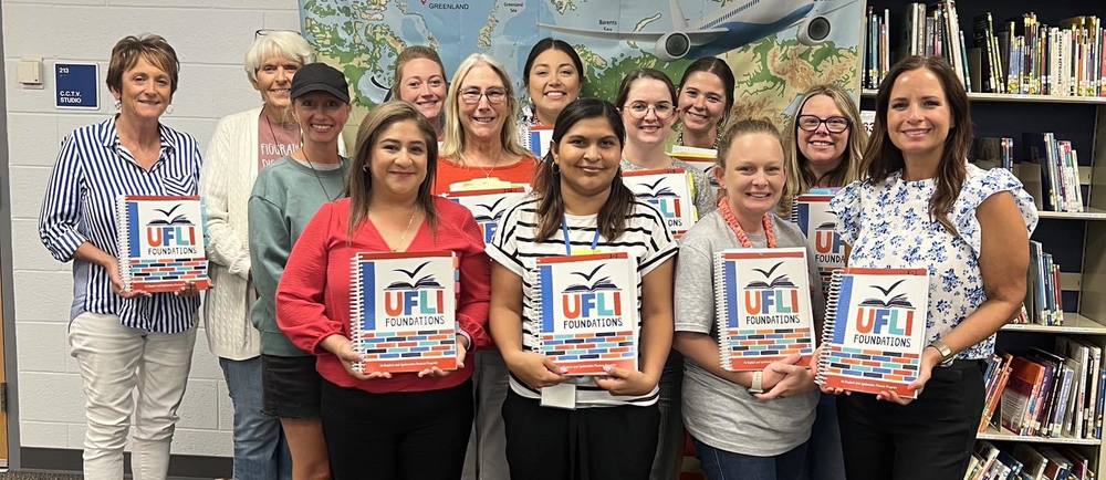 A group of teachers holding up the new phonics reading books that will be used in the 2025-2026 school year