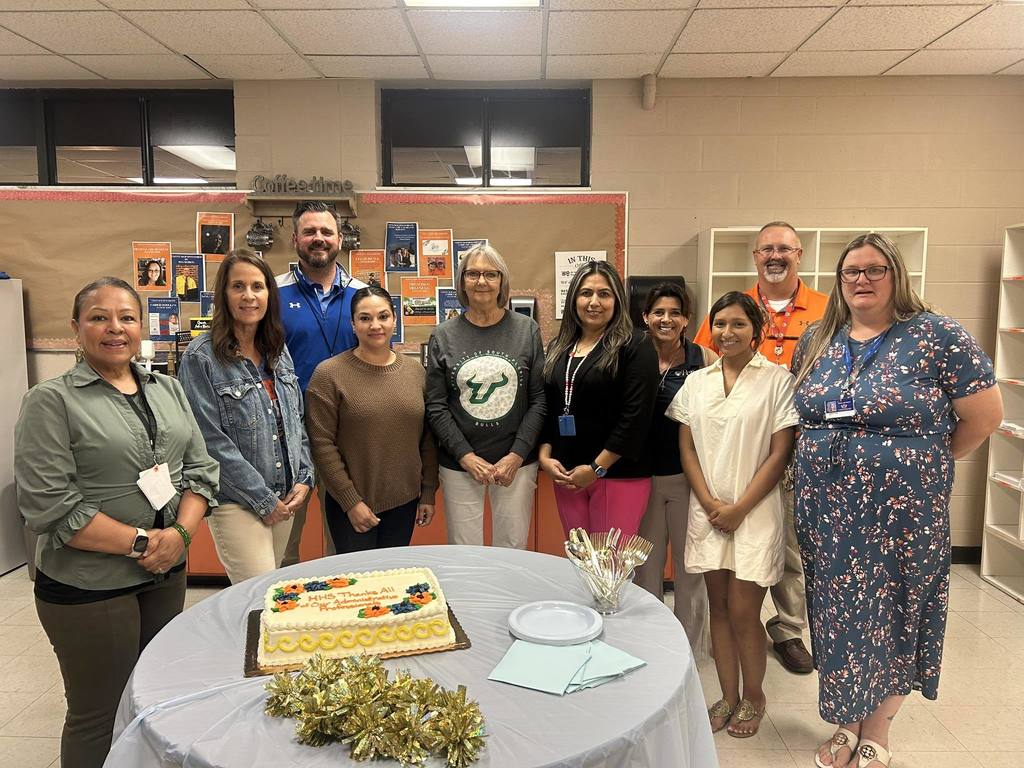 HHS administration team around a cake