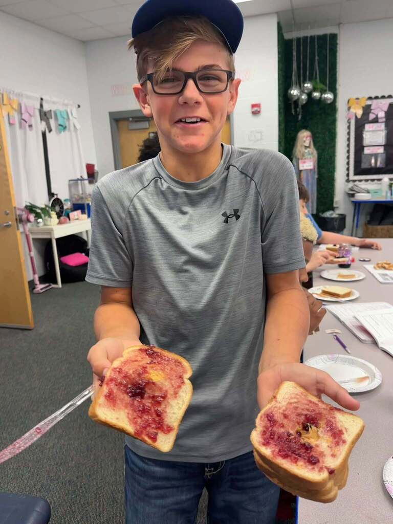 student holding two slices of bread with jam on them
