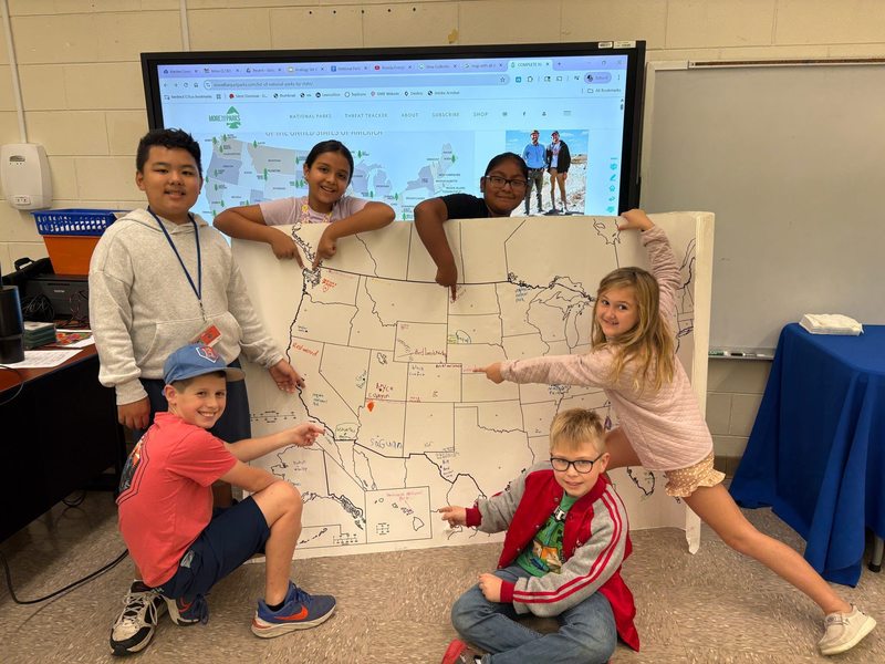 Students with a large map of the USA with national parks marked on it