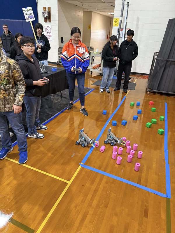 students moving robots through an obstacle course with controlers
