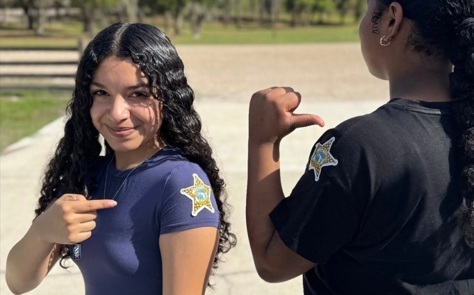 Student pointing to the sheriff badge sticker on her shoulder