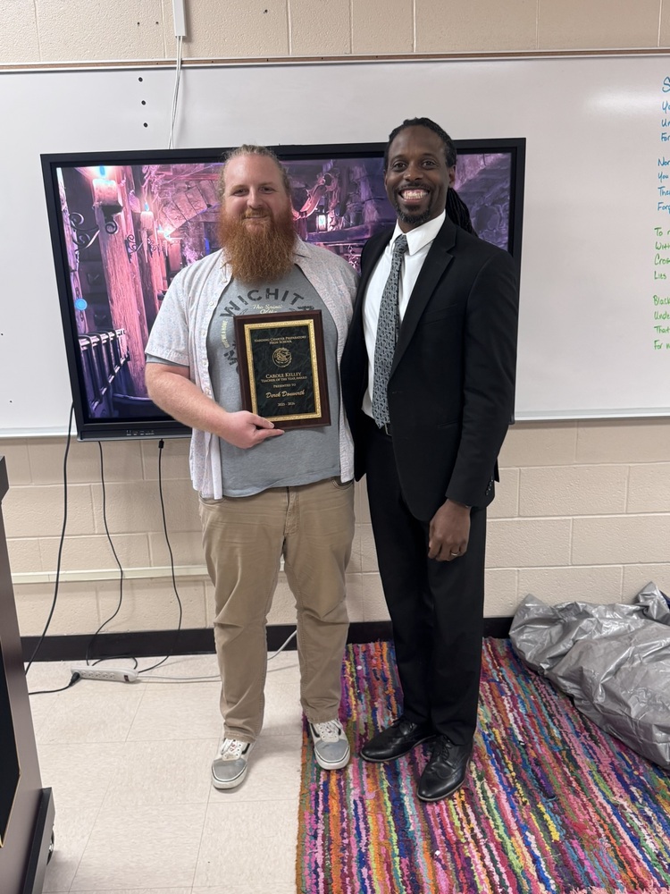 Derek Donwerth, HCPHS's Teacher of the Year, smiles as he holds his award and takes a photo with Principal Joe Hughes.
