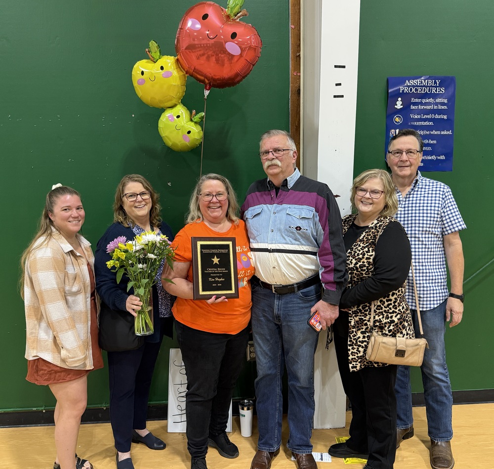Kim Hughes, HCPES's Teacher of the Year, smiles as she holds her award and is surrounded by her proud family.