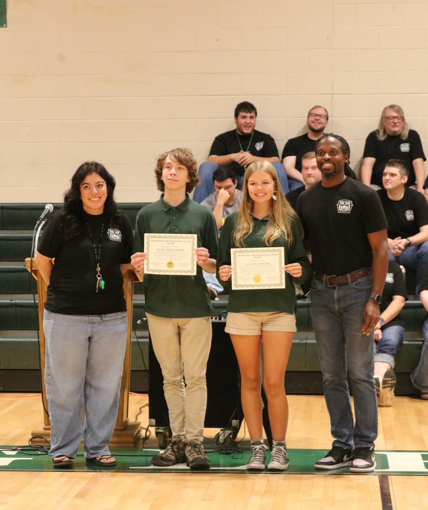 A group of AP Scholars holding certificates in a gymnasium next to their High School Principal and Assistant Principal.