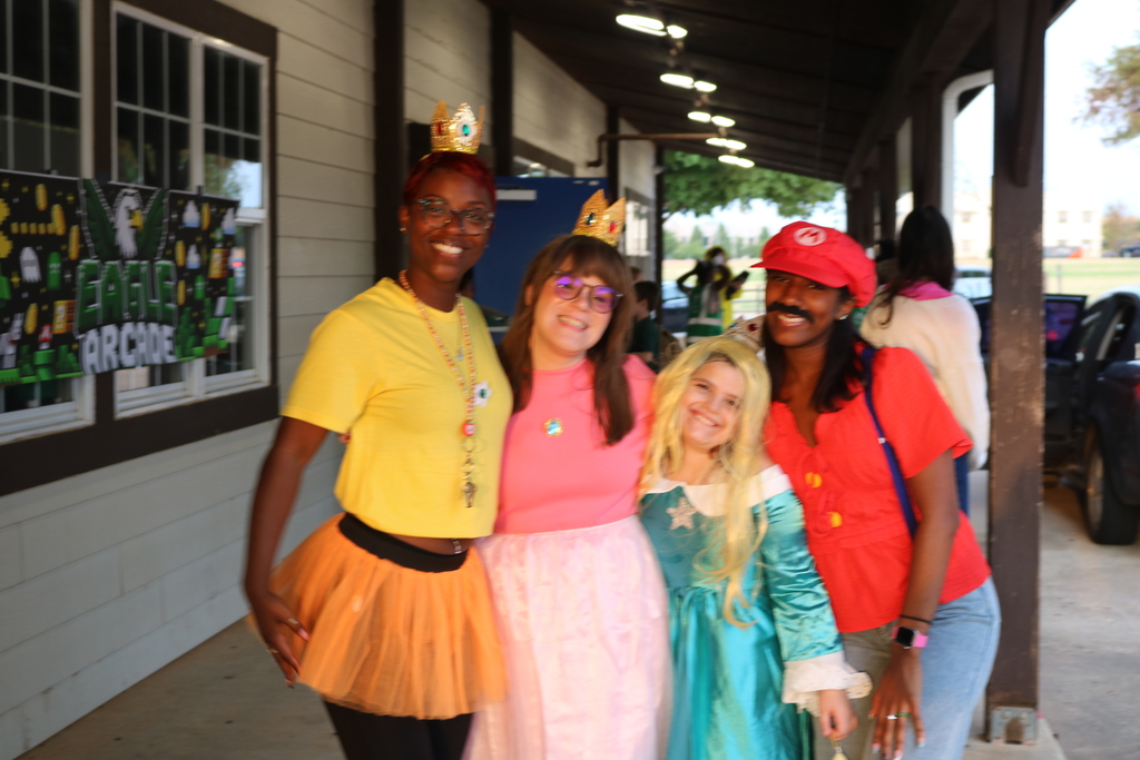 Four people dressed in costumes, two in yellow, one in pink, and one in red, pose for a photo.