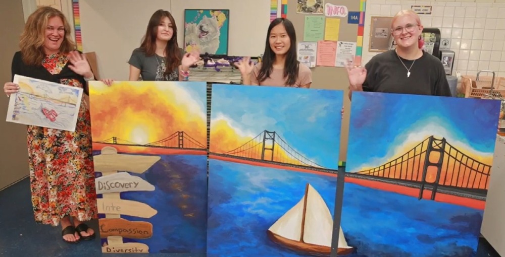 Students stand with mural;