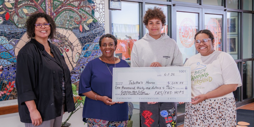 Three adults and one student stand with a large check showing a donation of more than $1,000 to Tabitha's House.