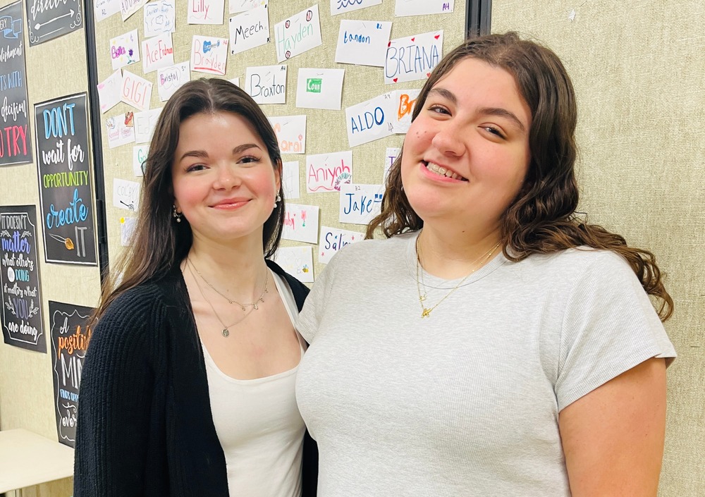Two students pose together smiling