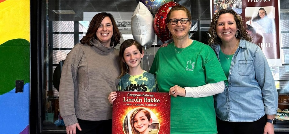 Four people standing in a hallway smiling