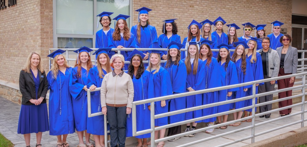 Group of students and professionals pose for a photo against a brick building