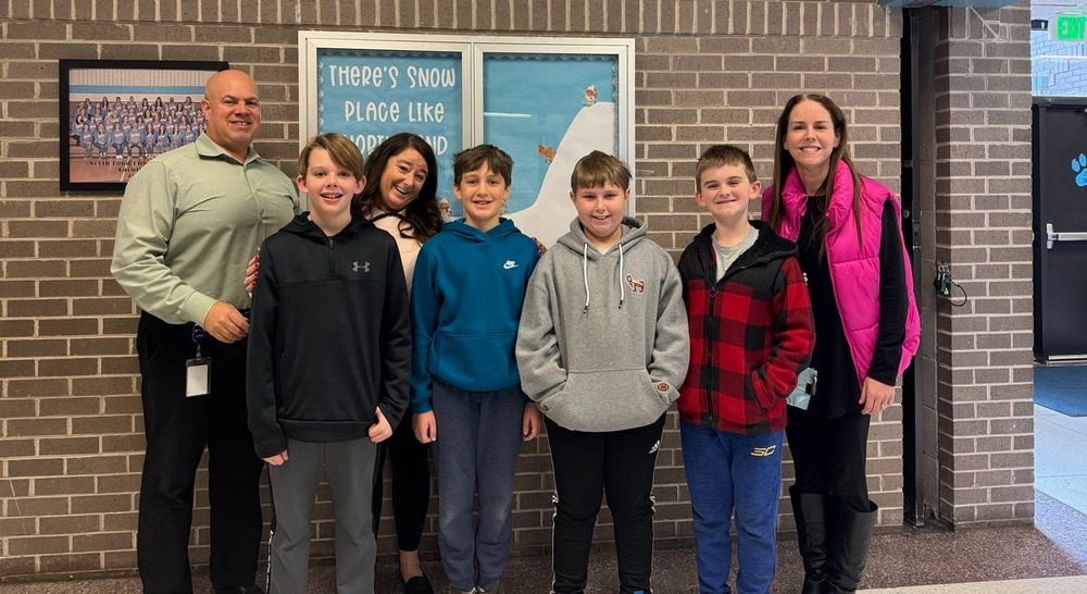 Group of students and educators stand in front of a brick wall