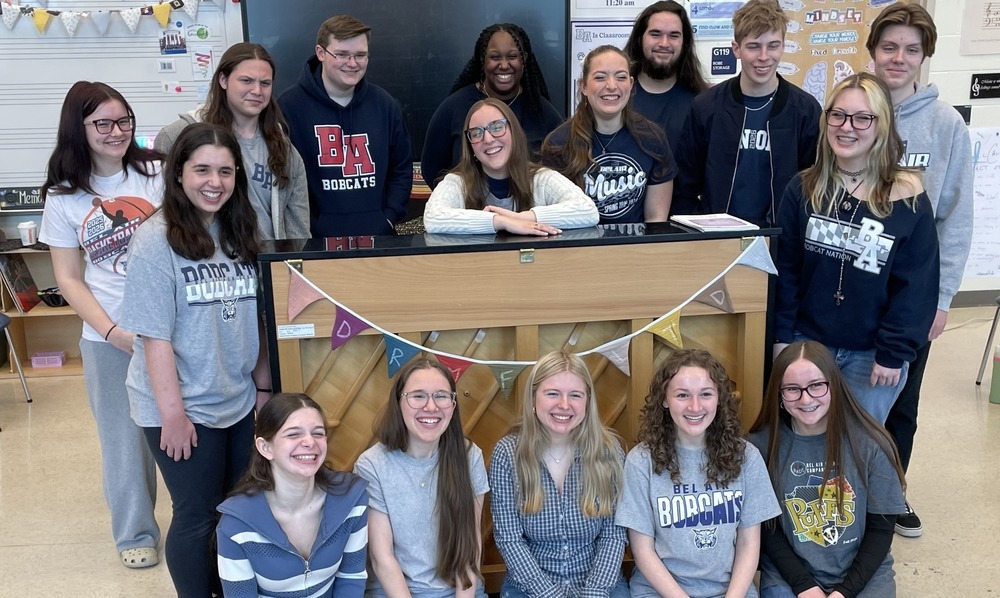 Teacher and students gather around piano