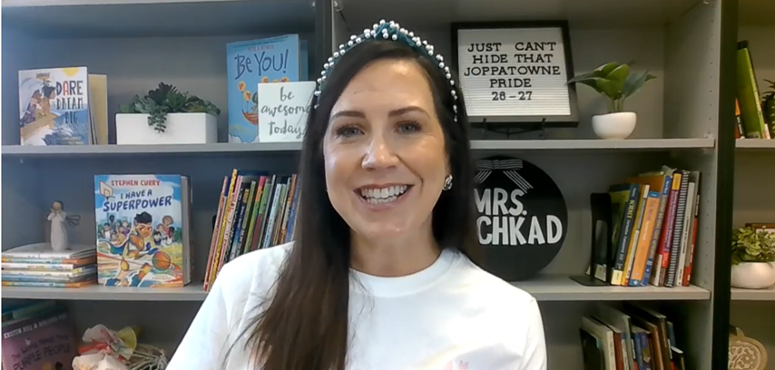 Woman with long hair in a white shirt wearing a headband smiling for the camera