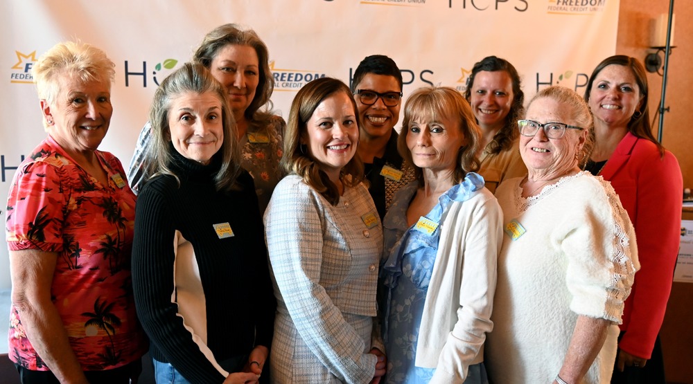 Group of women standing together and smiling in front of a HCPS and Freedom Federal Credit Union backdrop