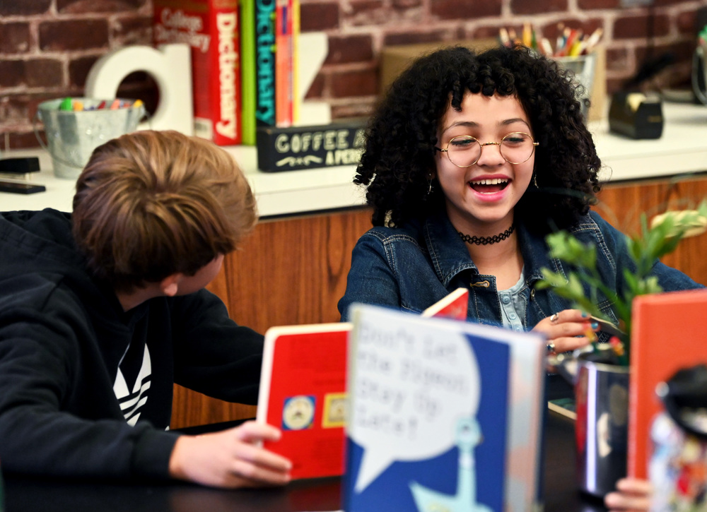 Two students smiling and looking at books