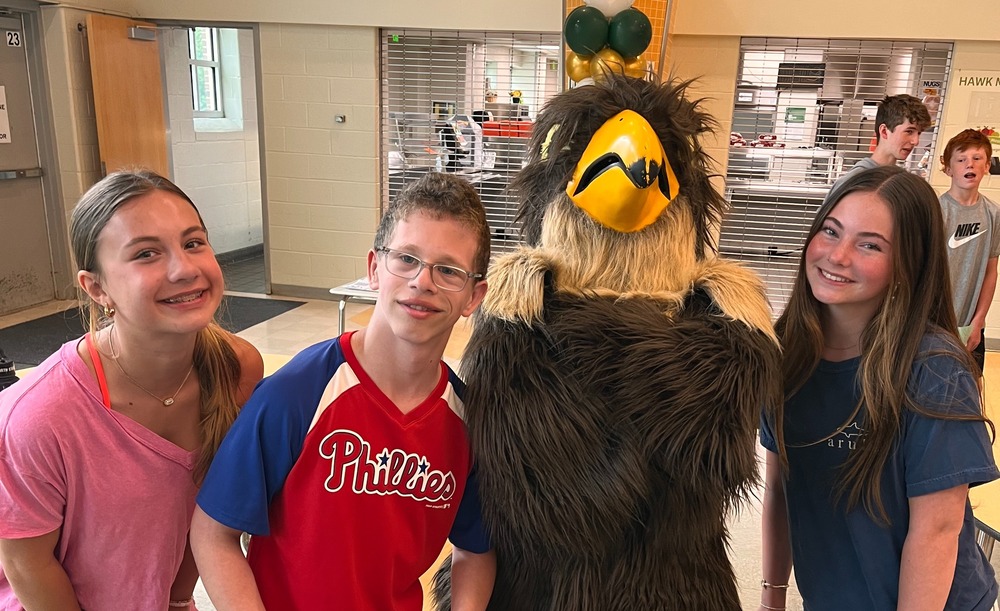 Three students pose with a hawk mascot