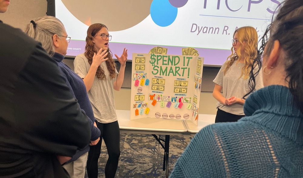 Students show their Spend it Smart work to a group of adults