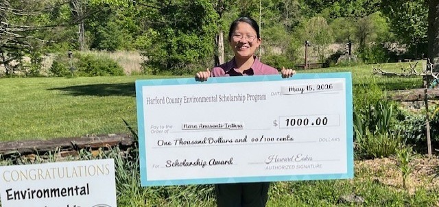 Student smiles while holding giant fake check