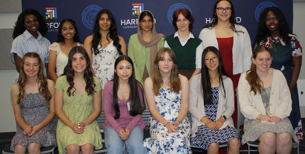 Group of young women seated and standing in front of a Harford Community College Backdrop