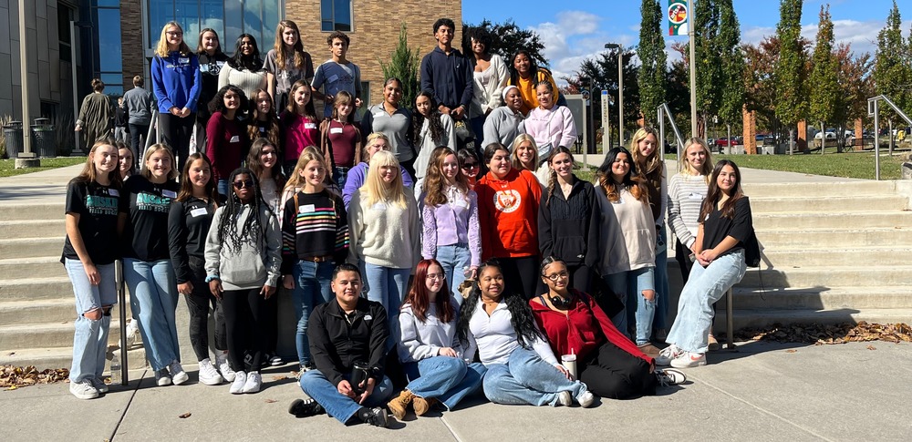 Group of students sitting on steps and posing for a photo
