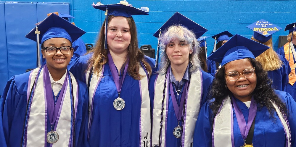 Group of four graduates in blue cap and gowns
