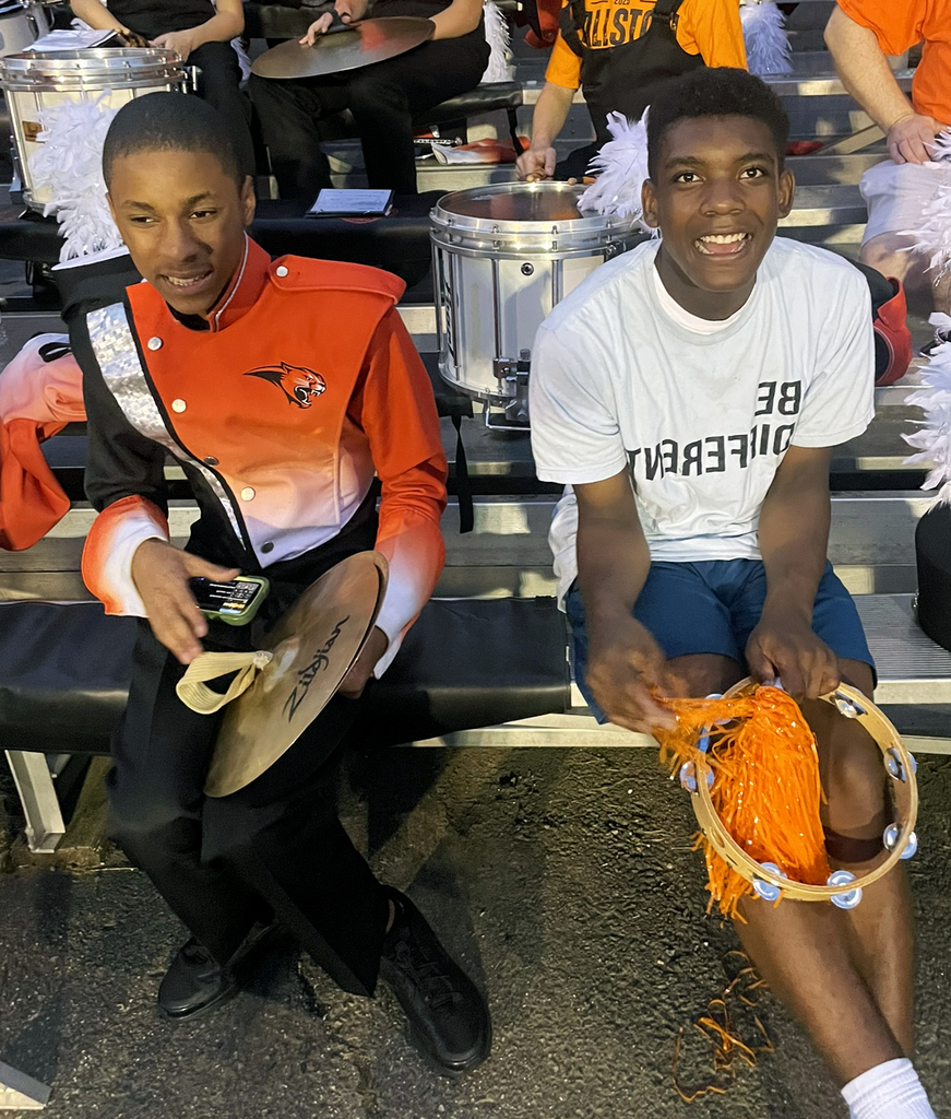 Two students in the stands. one with cymbols and the other holding a tambourine