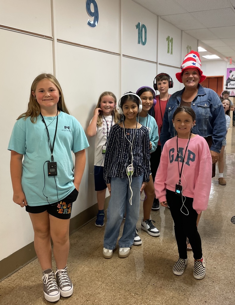 Students pose with teacher in hallway