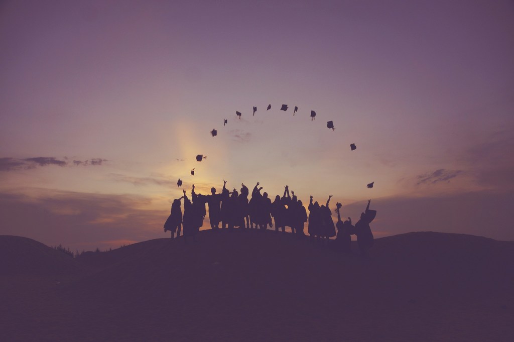 Graduates tossing caps in air forming an arc