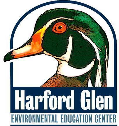 A logo illustration of a wood duck's head in profile, with vivid green, white, and rust-brown plumage and an orange bill, set against a white arched background. Below the illustration, text reads 'Harford Glen' in bold white letters on a navy blue banner, with 'ENVIRONMENTAL EDUCATION CENTER' in smaller navy blue text beneath