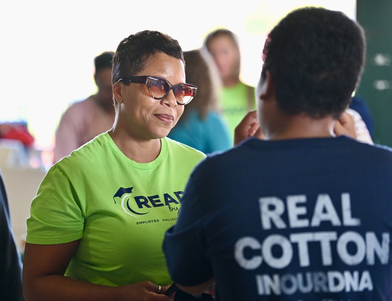 Dr. Mack, wearing a green shirt, speaks with a person in a blue shirt