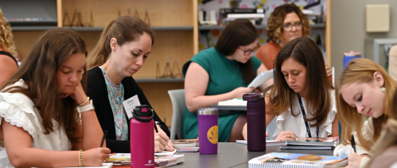 Group of new teachers istting around a table writing