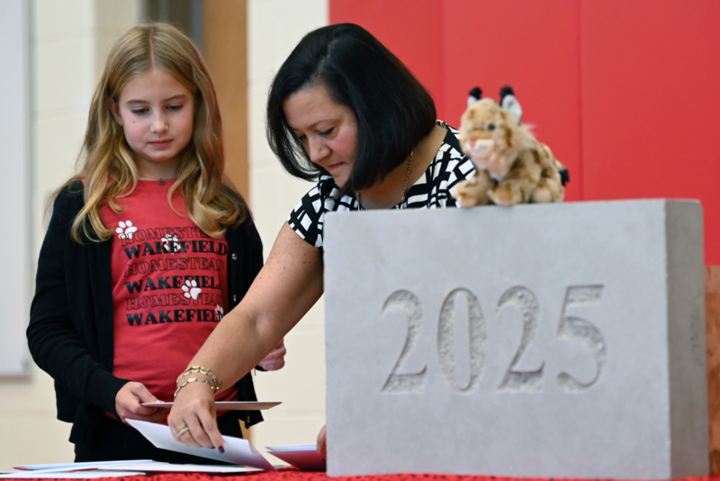 Student and staff member prepare a document to add to the corner stone